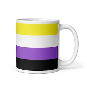 Peut inclure: Mug en céramique blanche avec le drapeau de la fierté non binaire. Le drapeau présente des rayures horizontales jaunes, blanches, violettes et noires. La tasse a une anse incurvée et une finition brillante.