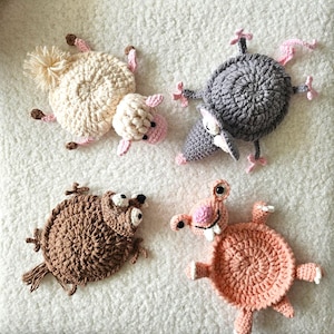 May include: Four handmade crochet animal toys: a sheep, a mouse, a brown creature, and a pink creature. The sheep is cream-colored with pink accents. The mouse is gray with pink details. The other two creatures are brown and pink.