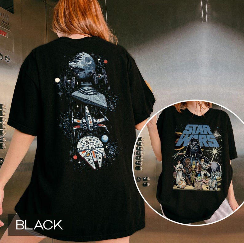 May include: A black t-shirt featuring a vertical space-themed graphic on the back with the Death Star, TIE fighters, a Star Destroyer, an X-wing, and the Millennium Falcon. The front displays a Star Wars logo with various character illustrations.