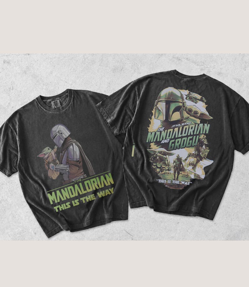 May include: A black short-sleeve t-shirt featuring a graphic of The Mandalorian and Grogu. The front displays the characters with the text "THE MANDALORIAN THIS IS THE WAY". The back features a larger collage of the characters and the text "THE MANDALORIAN AND GROGU" and "THIS IS THE WAY".