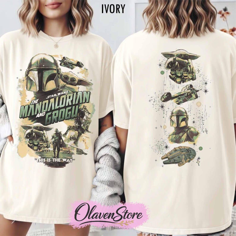 May include: An ivory t-shirt featuring Star Wars graphics. The front displays The Mandalorian and Grogu with the text "The Mandalorian and Grogu" and "This is the way." The back shows a vertical arrangement of Grogu, a starship, a helmet, and a ship.
