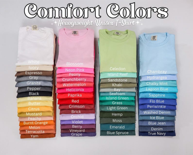 May include: A collection of Comfort Colors heavyweight unisex t-shirts arranged in four vertical stacks. Each stack displays a variety of solid colors, with labels printed on the fabric identifying shades like White, Ivory, Blossom, Neon Pink, Celedon, and True Navy.