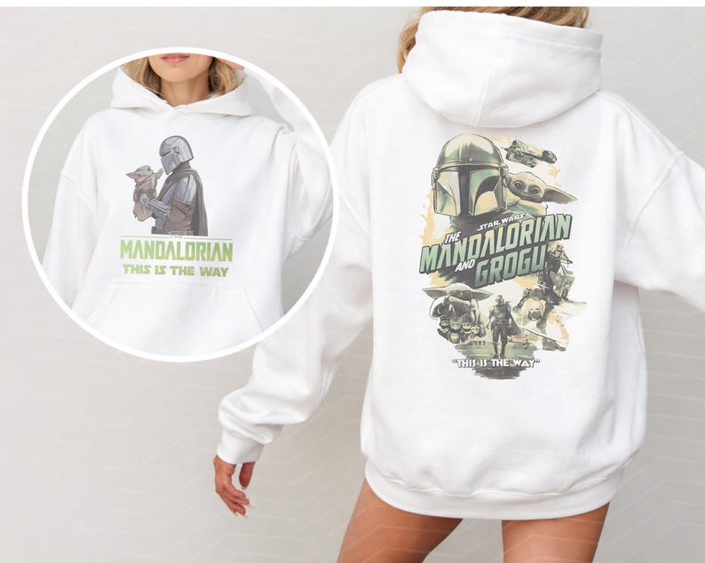 May include: A white hooded sweatshirt featuring a graphic of The Mandalorian and Grogu on the back with the text The Mandalorian and Grogu and This Is The Way. A circular inset shows the front of the hoodie with a smaller graphic and text.