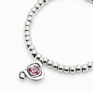 Peut inclure: Un bracelet argent&eacute; compos&eacute; de perles rondes. Il est orn&eacute; d'un charm en forme de Mickey Mouse avec une pierre rose carr&eacute;e sertie dans un cadre argent&eacute;.