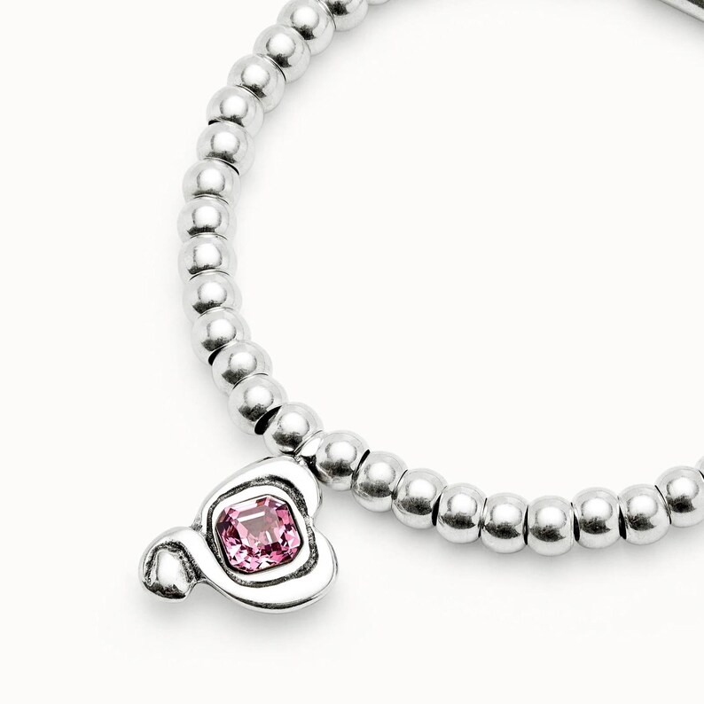 Peut inclure: Un bracelet argent&eacute; compos&eacute; de perles rondes. Il est orn&eacute; d'un charm en forme de Mickey Mouse avec une pierre rose carr&eacute;e sertie dans un cadre argent&eacute;.