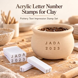 Puede incluir: Un juego de sellos de letras y números de acrílico blanco para arcilla, con bloques rectangulares de caracteres en relieve. Los sellos crean impresiones como JADA 2023 en una maceta de cerámica beige. Texto: Acrylic Letter Number Stamps for Clay.