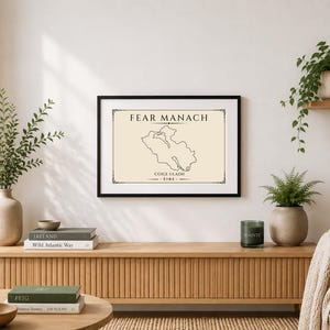 以下が含まれることがあります： クリーム色の背景にアイルランドのファーマナの黒い輪郭地図が描かれた、長方形の額入りアートプリント。黒いセリフ体で「FEAR MANACH」「CÚIGE ULADH」「ÉIRE」という文字が記されており、細い黒い枠線の中に中央揃えで配置されています。