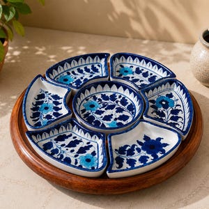 Puede incluir: Una bandeja de servicio circular de madera que contiene seis cuencos de cerámica en forma de abanico y un cuenco central redondo. Cada cuenco blanco presenta un patrón floral pintado a mano en tonos azul oscuro y azul claro con hojas.
