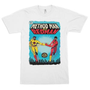 May include: A white short-sleeve t-shirt featuring a comic book style graphic of Method Man and Redman. The print shows two figures in yellow and red superhero costumes against a blue background with the text "METHOD MAN AND REDMAN".