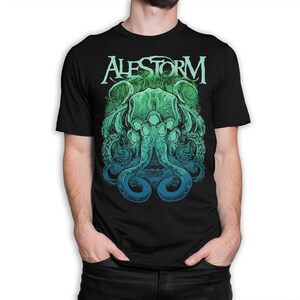 May include: A black short-sleeve t-shirt featuring a graphic print of a green and blue octopus-like creature with tentacles. The word ALESTORM is printed in a stylized white font above the creature, set against a circular green background.