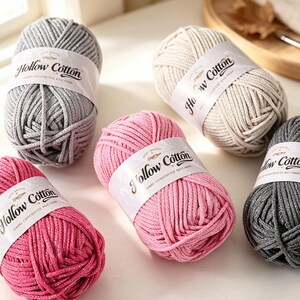 Peut inclure: Cinq pelotes de fil Hollow Cotton en argent, crème, rose clair, rose foncé et gris anthracite. Chaque pelote comporte une bande de papier blanc avec le texte Hollow Cotton imprimé en noir, indiquant que le fil est pour la garniture de sac.