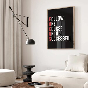 Könnte beinhalten: Ein rechteckiger Wandkunstdruck mit schwarzem Hintergrund und weißem Text, der FOLLOW ONE COURSE UNTIL SUCCESSFUL lautet, wobei die Buchstaben F, O, C, U, S rot hervorgehoben sind, um das Wort FOCUS vertikal auf der linken Seite zu bilden.