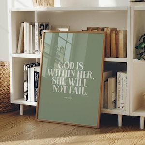 Può includere: Un quadro rettangolare con cornice caratterizzato da uno sfondo verde salvia e una tipografia bianca con grazie che recita: GOD IS WITHIN HER, SHE WILL NOT FAIL. PSALM 46:5. La stampa è racchiusa in una sottile cornice in legno chiaro con vetro.