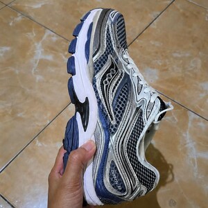 May include: A running shoe with a white, blue, and silver color scheme. The shoe features a mesh upper, a cushioned sole, and the text "omni 9" on the side. The shoe is designed for athletic activities.
