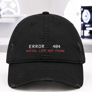 May include: A black baseball cap with a distressed, worn-in finish. The front features white embroidered text that reads ERROR 404, with the red embroidered text SOCIAL LIFE NOT FOUND positioned directly underneath the error code.