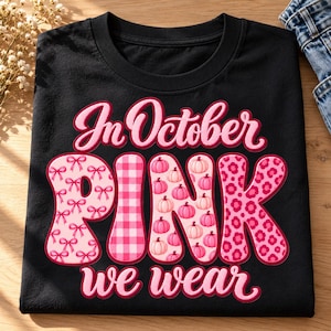 Op de afbeelding: Een zwart t-shirt met de tekst In October PINK we wear. Het woord PINK is groot en gevuld met verschillende patronen, waaronder roze strikjes, een roze ruitpatroon, roze pompoenen en een roze bloemachtig luipaardpatroon.