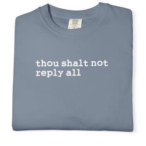 May include: A slate blue crew neck t-shirt featuring the white text "thou shalt not reply all" printed across the chest. The garment has a standard short-sleeve design and includes a visible interior neck label from the brand Comfort Colors.