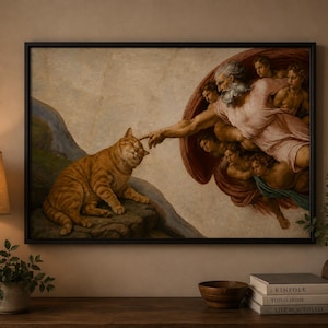 May include: Framed art print depicting a humorous take on Michelangelo's 'The Creation of Adam.' The artwork features a tabby cat in place of Adam, with God's finger touching the cat's head. The print is in a black frame.