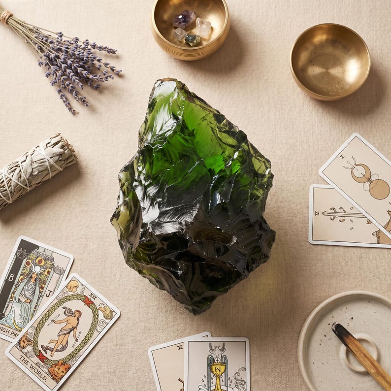 Large green Andara-style obsidian glass chunk resting on a simple altar with incense and brass accents, designed for sacred space decor and crystal display.