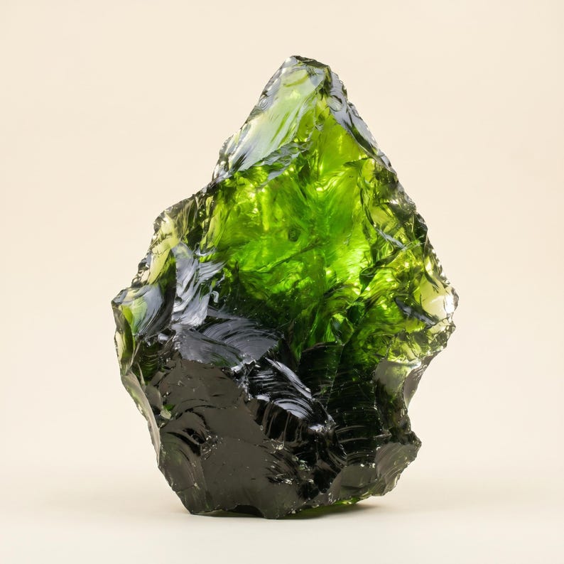 Angled view of a transparent green uncut gemstone specimen with olive smoky zones, reflective surfaces, and thick glass-like clarity for crystal collectors.