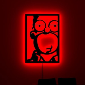 May include: A rectangular wall-mounted light fixture featuring a black cutout silhouette of a cartoon character face with a prominent mouth and eyes. The design is illuminated from behind by a vibrant red LED glow, creating a stark contrast.