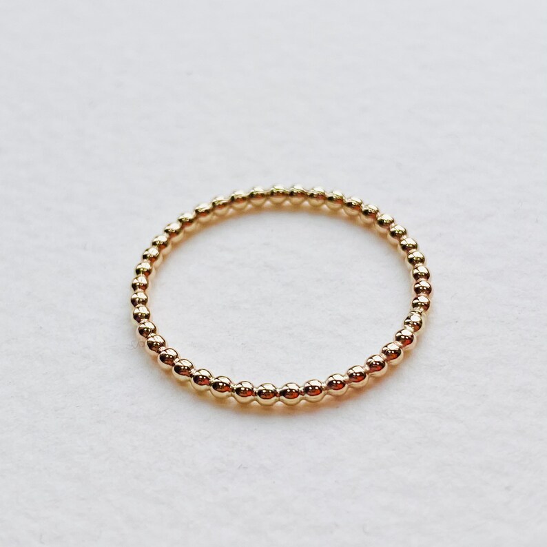 Puede incluir: Un anillo de oro con cuentas de dise&ntilde;o sencillo. El anillo est&aacute; hecho de peque&ntilde;as cuentas redondas que est&aacute;n espaciadas uniformemente.