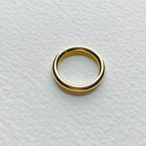 Puede incluir: Un aro para la oreja de color dorado con un acabado liso y pulido.