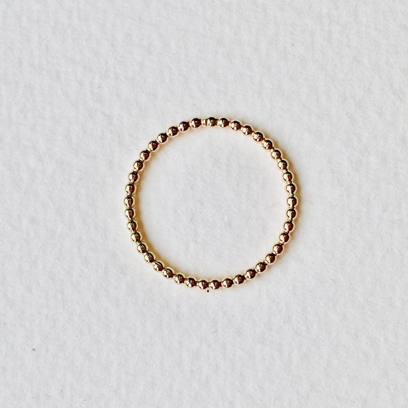 Puede incluir: Un anillo de oro con cuentas de dise&ntilde;o sencillo. El anillo est&aacute; hecho de peque&ntilde;as cuentas redondas que est&aacute;n conectadas entre s&iacute; para formar un c&iacute;rculo.