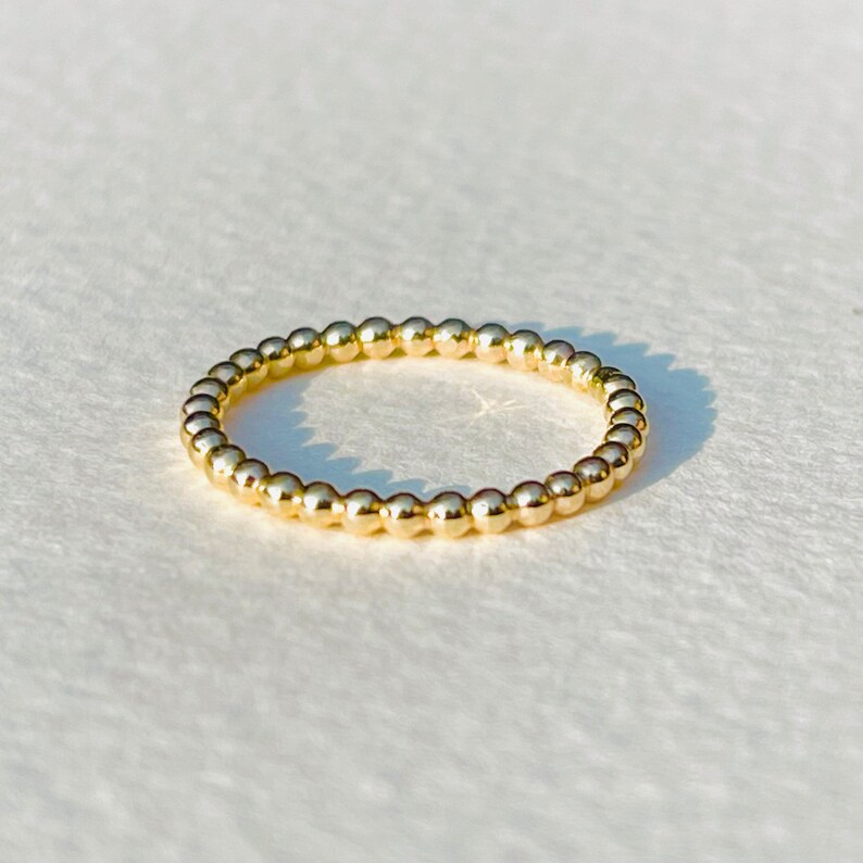 Puede incluir: Un anillo de oro con cuentas de dise&ntilde;o sencillo. El anillo est&aacute; hecho de peque&ntilde;as cuentas redondas que est&aacute;n espaciadas uniformemente.