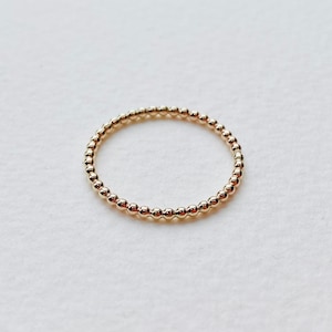 Puede incluir: Un anillo de oro con cuentas de dise&ntilde;o simple y minimalista.
