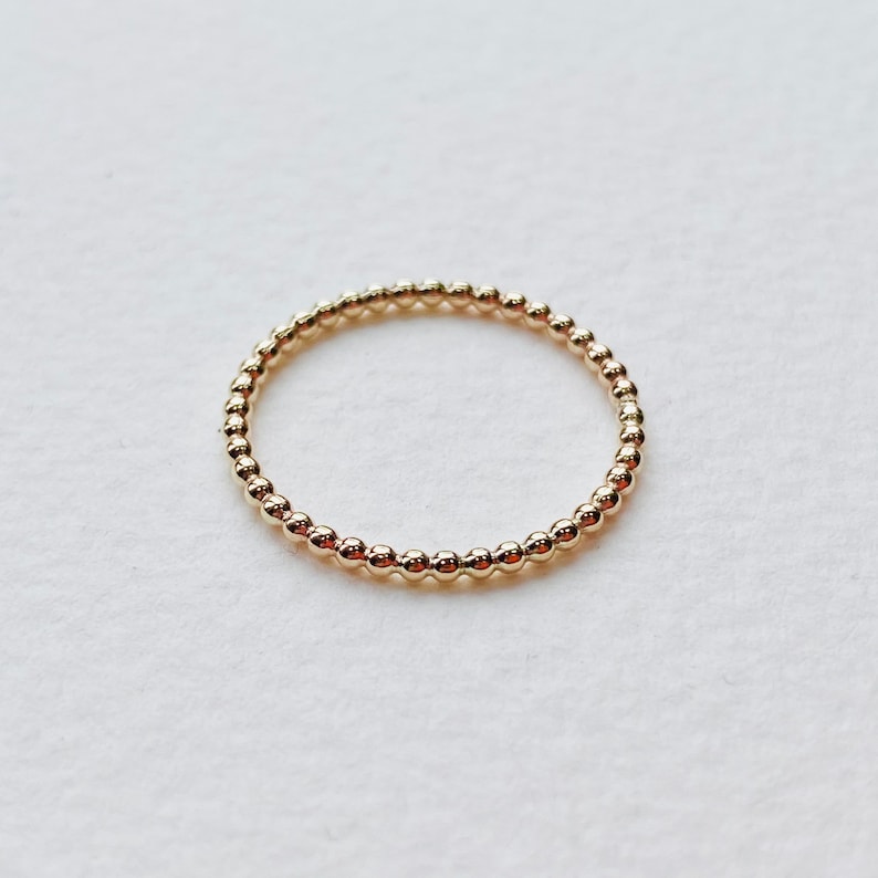 Puede incluir: Un anillo de oro con cuentas de dise&ntilde;o simple y minimalista.