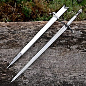 May include: A silver-toned metal sword with a pointed blade and a white wrapped handle featuring a rounded pommel. The sword is accompanied by a matching white scabbard with silver-toned metal fittings, including a pointed tip and a top band.
