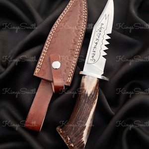 Puede incluir: Un cuchillo de hoja fija con lomo dentado, hoja plateada con inscripciones grabadas y mango de asta marrón texturizada. El cuchillo incluye una funda de cuero marrón a juego con costuras decorativas y un cierre de botón a presión.