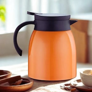 Könnte beinhalten: Eine leuchtend orangefarbene Thermokanne mit einem mattschwarzen Deckel und einem passenden schwarzen, geschwungenen Griff. Das Gefäß hat einen glatten, abgerundeten Körper mit einem kleinen Ausguss zum sicheren Aufbewahren von Flüssigkeiten.