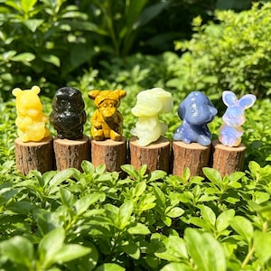 以下が含まれることがあります： 黄色、黒色、タイガーアイ、淡い緑色、青色、虹色の白色など、様々な宝石から彫られた6体の小さな動物の置物。それぞれの置物は、小さな円筒形の粗削りな木の台座の上に置かれています。