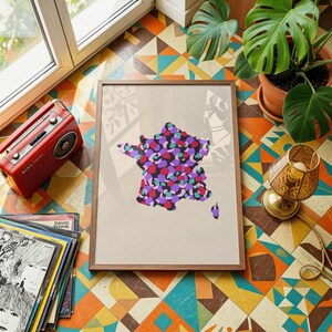 May include: A framed wall art print featuring a map of France filled with a colourful pattern of overlapping purple, pink, and teal circular shapes against a light beige background, enclosed in a simple brown wooden frame.