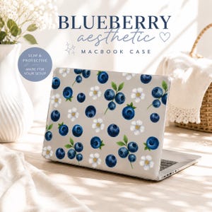 May include: A laptop with a "Blueberry Aesthetic" Macbook case. The case features a pattern of dark blue blueberries, green leaves, and small white flowers on a light gray background. The case is labeled "Slim & Protective" and "Made for your setup."
