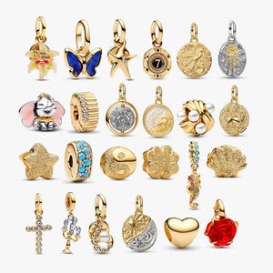 May include: A collection of gold-toned charms with various designs, including a butterfly, starfish, and a seahorse. Some charms feature gemstones, pearls, and enamel details. The charms are designed for bracelets or necklaces.