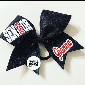May include: Black glitter cheer bow with white text that says "Senior" and red text that says "#NoMore". The bow also has red text that says "Gianna" and a white circle with black text that says "Triple O Bows".