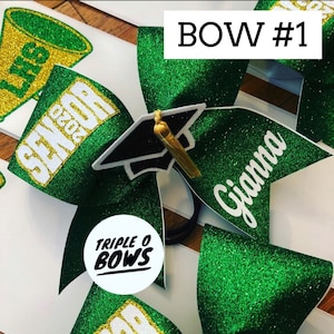 Puede incluir: Lazo de animadora con purpurina verde con el texto "Gianna" en blanco. El lazo presenta un gorro de graduaci&oacute;n y el texto "SENIOR 2020". El lazo est&aacute; etiquetado como "BOW #1" y tiene el logotipo "TRIPLE O BOWS".