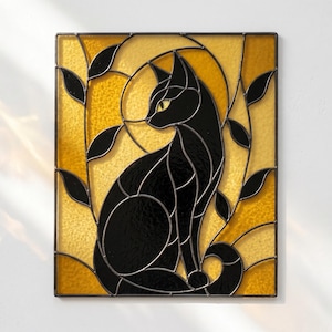May include: A rectangular stained glass panel featuring a black cat silhouette centered against a textured amber and yellow background. The cat is surrounded by black glass leaf motifs, all held together by dark metal lead lines in a geometric design.