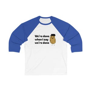 May include: White and blue raglan baseball tee with the text "We're done when I say we're done" and a cartoon potato wearing a hat. The shirt has blue sleeves and a white body.