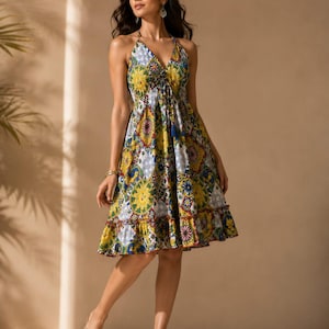 May include: A knee-length halter dress featuring a vibrant, multicolored pattern of yellow, blue, and white geometric and floral motifs. The dress has a deep V-neckline, a cinched waist with a tassel detail, and a ruffled hemline at the bottom.