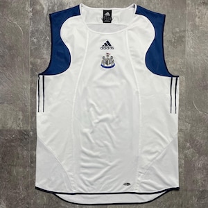 Puede incluir: Camiseta de f&uacute;tbol blanca sin mangas con detalles azul marino en hombros y laterales. Presenta el logo de Adidas y el escudo del equipo en el pecho. Tres rayas azul marino a cada lado.