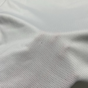 Puede incluir: Primer plano de una tela gris claro con un patr&oacute;n texturizado y perforado. La tela parece ser un material transpirable, posiblemente para ropa deportiva. La imagen resalta los finos detalles del tejido.