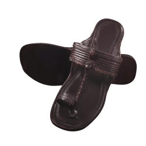 May include: Dark brown leather sandals with a toe loop and strap detail. The sandals have a flat sole and are designed for comfort and style. The leather appears to be well-crafted, with visible stitching and a classic design.