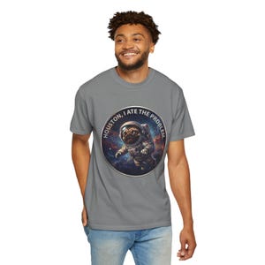 A man wearing a grey t-shirt featuring the space pug graphic and blue jeans, looking off to the side with a smile.