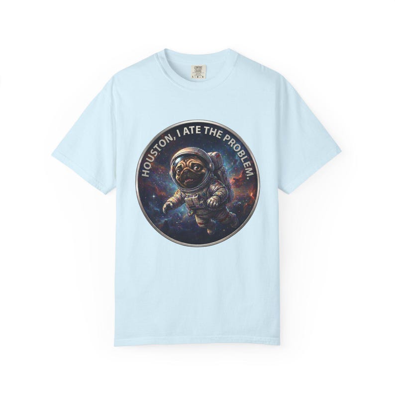A light blue crewneck t-shirt featuring a circular graphic of a pug in an astronaut suit floating in space with the text HOUSTON, I ATE THE PROBLEM.