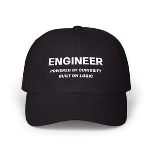 May include: A black baseball cap featuring white embroidered text on the front that reads ENGINEER, POWERED BY CURIOSITY, BUILT ON LOGIC. The cap has a structured crown, a curved brim, and a button at the top centre of the fabric panels.