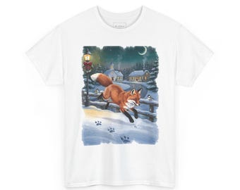 May include: A white t-shirt featuring a graphic illustration of a red fox leaping through deep snow. The scene includes a dark winter night, a glowing street lamp, small birds, and snow-covered houses in the background with a crescent moon.